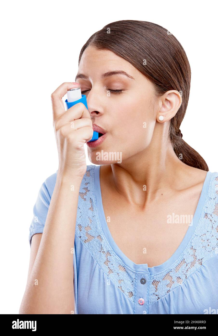Zum Glück hatte sie ihren Inhalator dabei. Studioaufnahme einer attraktiven jungen Frau, die einen Asthma-Inhalator verwendet. Stockfoto