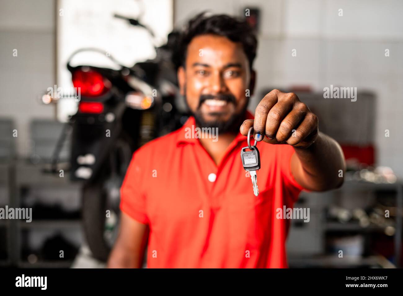 Konzentrieren Sie sich auf die Hände, Mechaniker zeigen auf Motorrad-Schlüssel durch Blick auf die Kamera - Konzept der Fertigstellung der Wartung, selbstbewusst und professionell Stockfoto