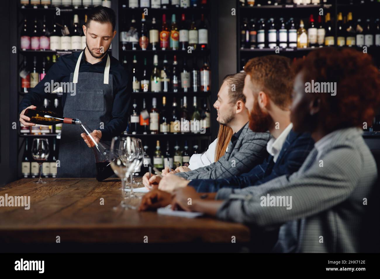 Männlicher Sommelier führt für Restaurantgäste eine Rotweinverkostung durch. Stockfoto