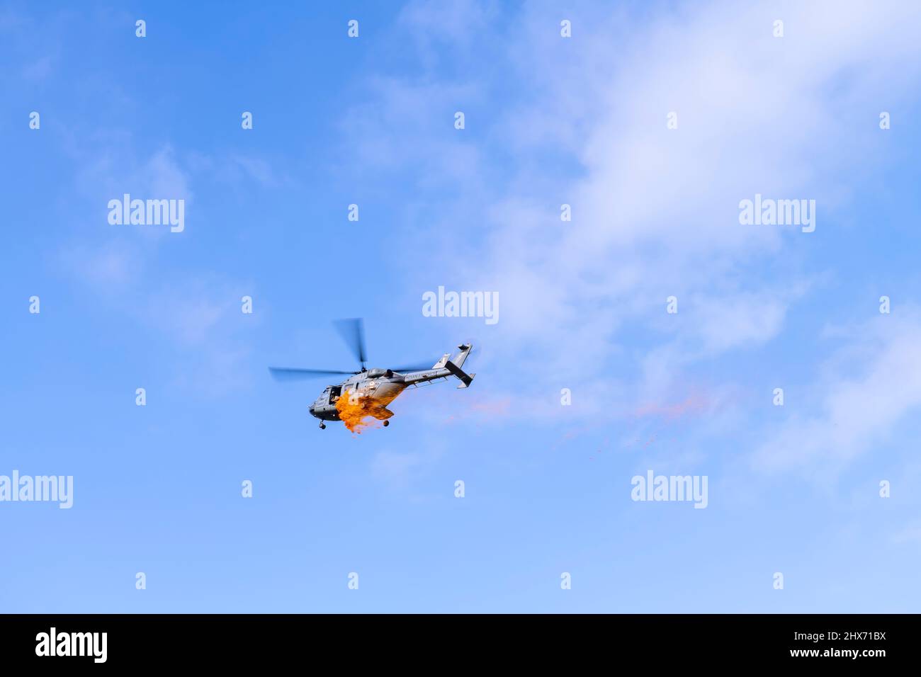 Ein Hubschrauber der indischen Luftwaffe, Dhruv, wirft Blütenblätter auf die Menschen, die sich am Tag der indischen Republik auf dem Boden versammelten. Stockfoto