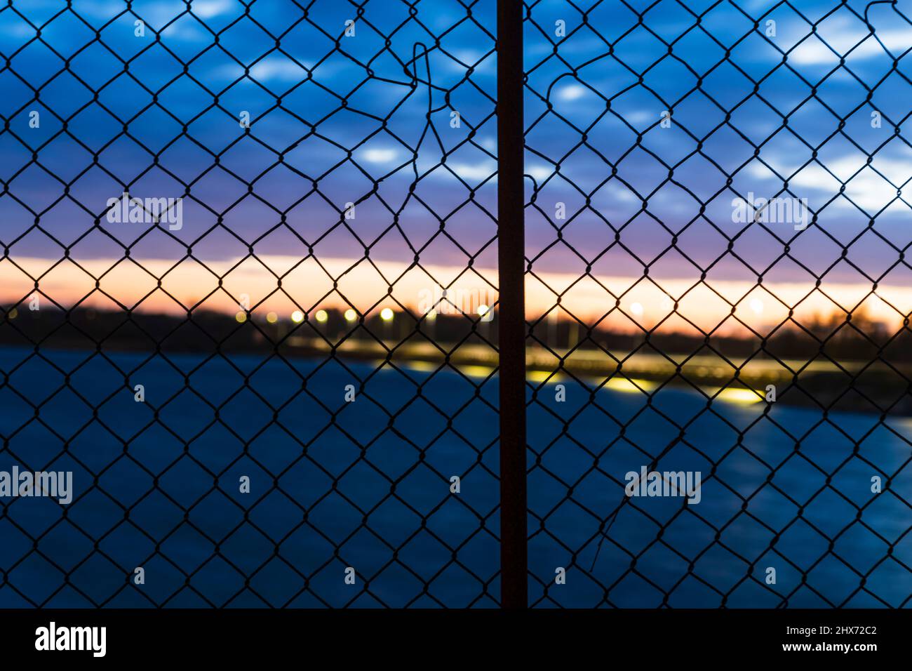 Sonnenuntergang Himmel durch Kettenglied Zaun gesehen Stockfoto