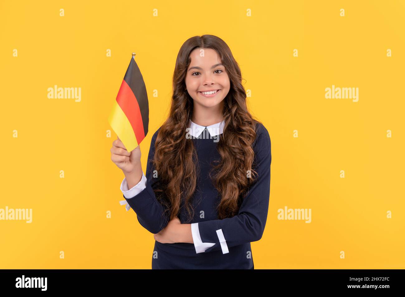Glückliches Kind halten deutsche Flagge gelben Hintergrund, studieren im Ausland Stockfoto