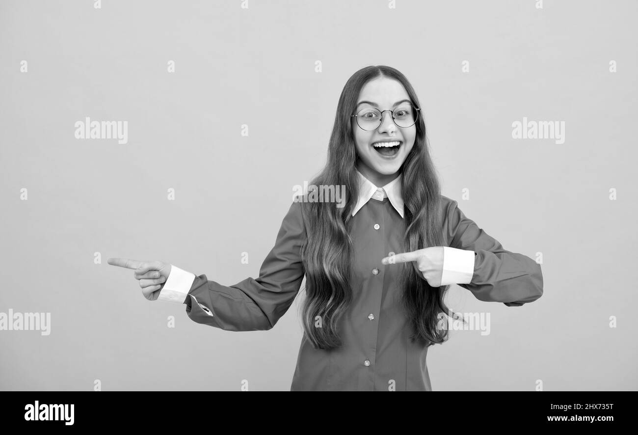 Glücklich zurück zur Schule Mädchen Lächeln zeigt Finger gelb Hintergrund Kopie Raum, Verkauf Stockfoto
