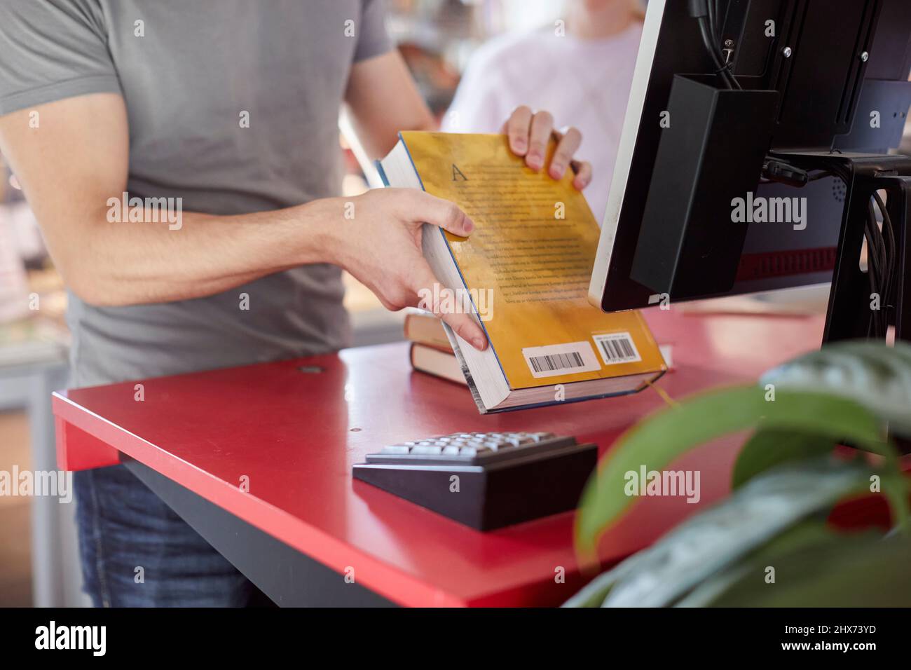 Männlicher Student, der Buch in der Bibliothek scannt Stockfoto