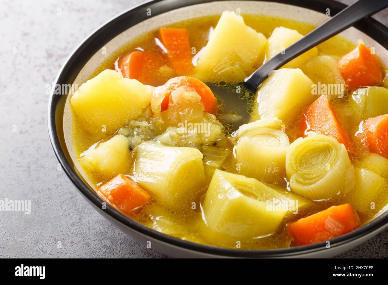 Authentische spanische Gemüsesuppe aus der Nähe von Porturusalda in einer Schüssel auf einem Betontisch. Horizontal Stockfoto