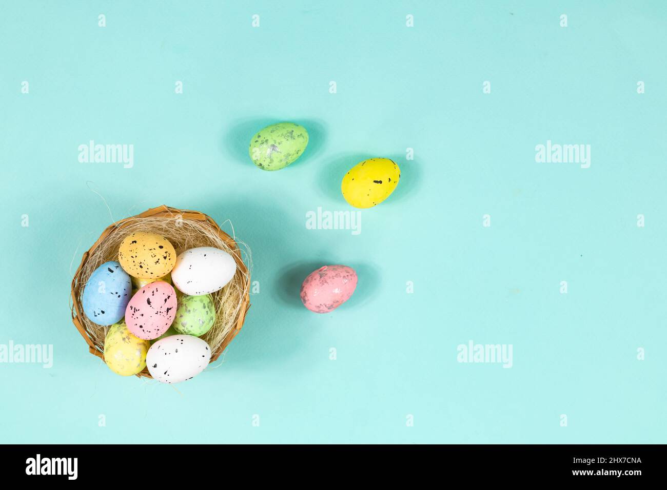 Mehrfarbige Ostereier in einem Nest auf blauem Hintergrund mit Platz für Text, Beschriftung. Basis für eine Postkarte, Draufsicht. Stockfoto