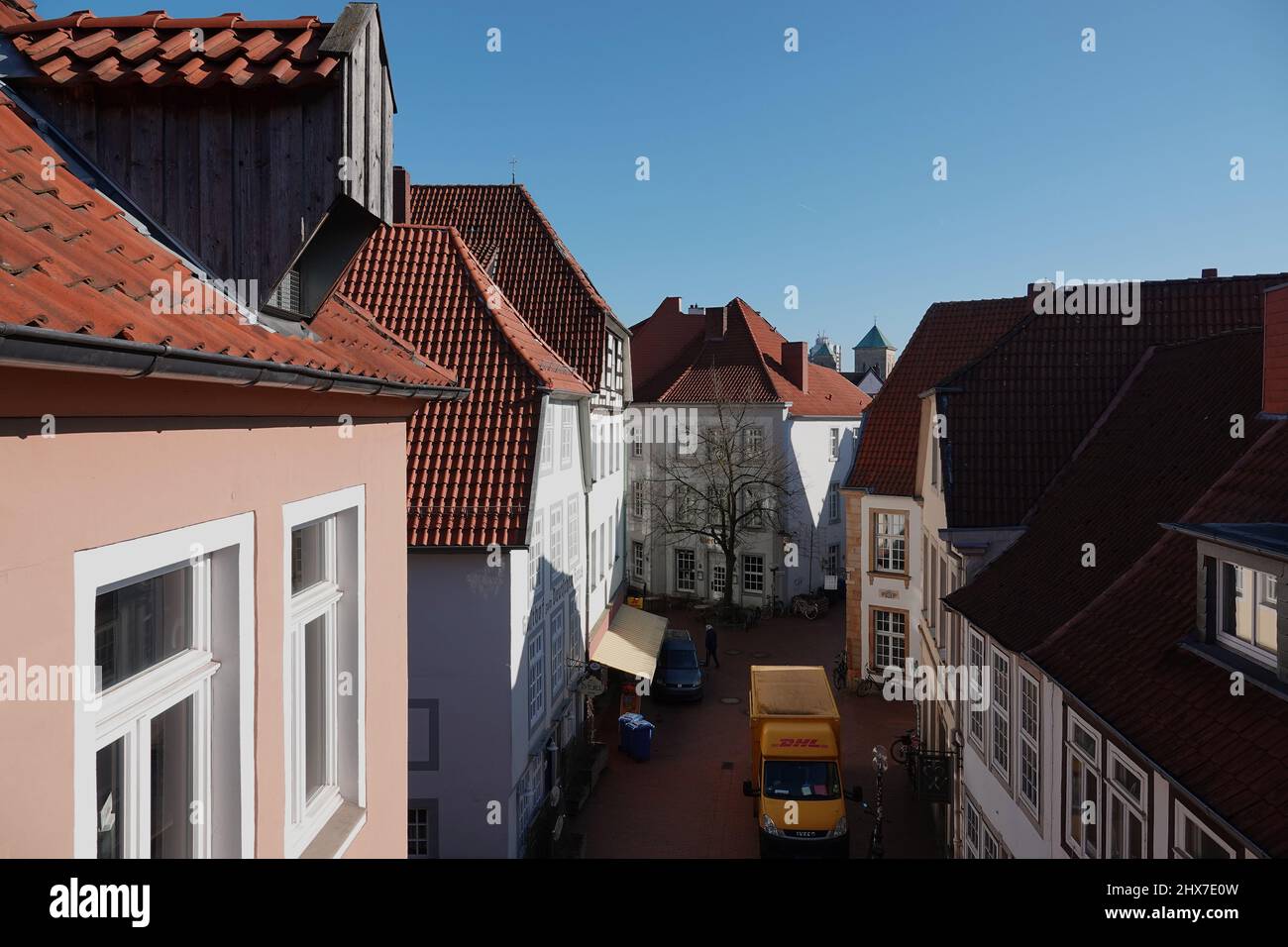 Osnabrück, Deutschland - März 8 2022 Blick von oben nach unten auf eine Straße mit historischen Häusern. Ein gelber Van des Zustelldienstes DHL ist auf der Straße Stockfoto