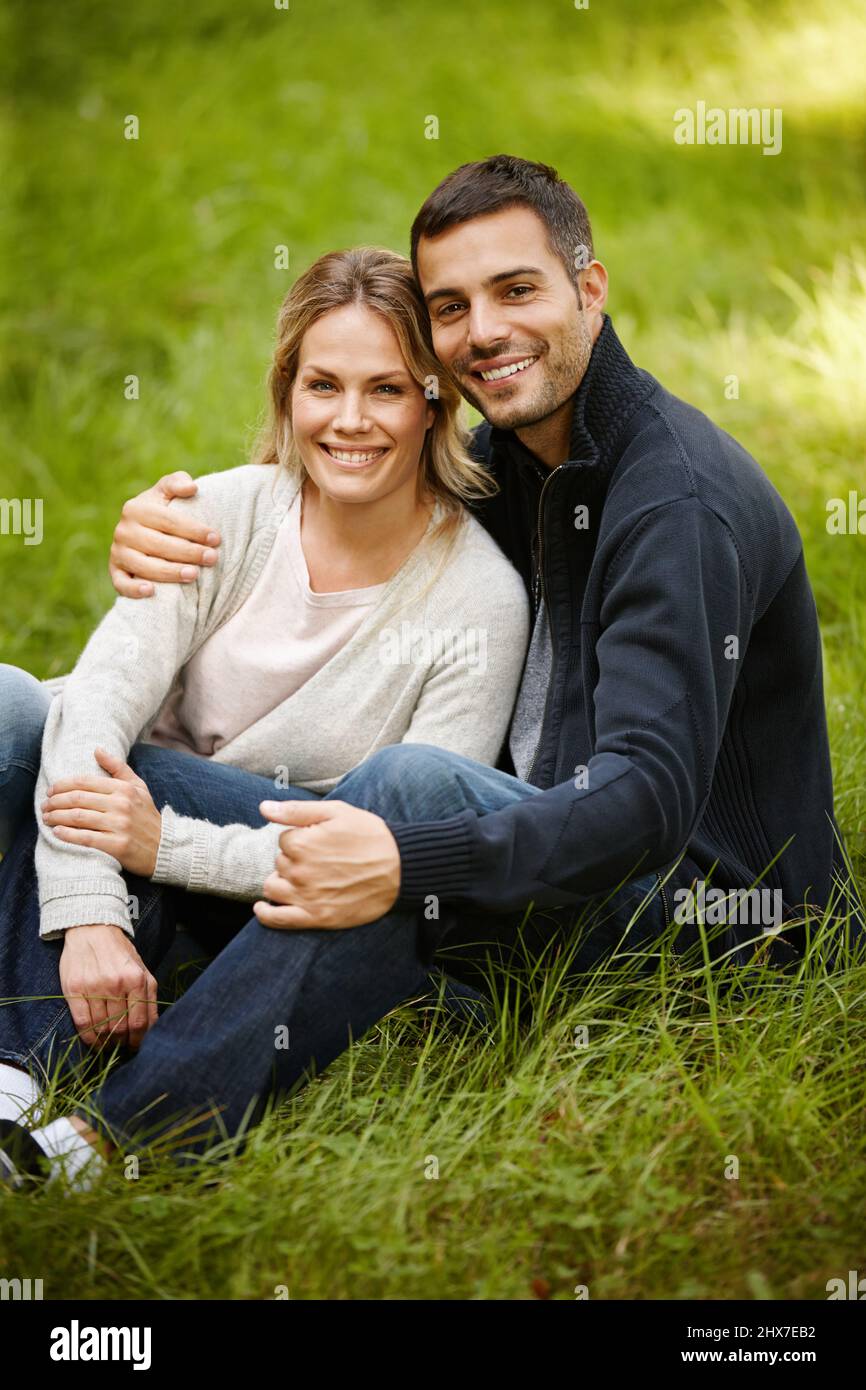 Parkromantik. Porträt eines liebenden jungen Paares, das auf dem Gras in einem Park sitzt. Stockfoto