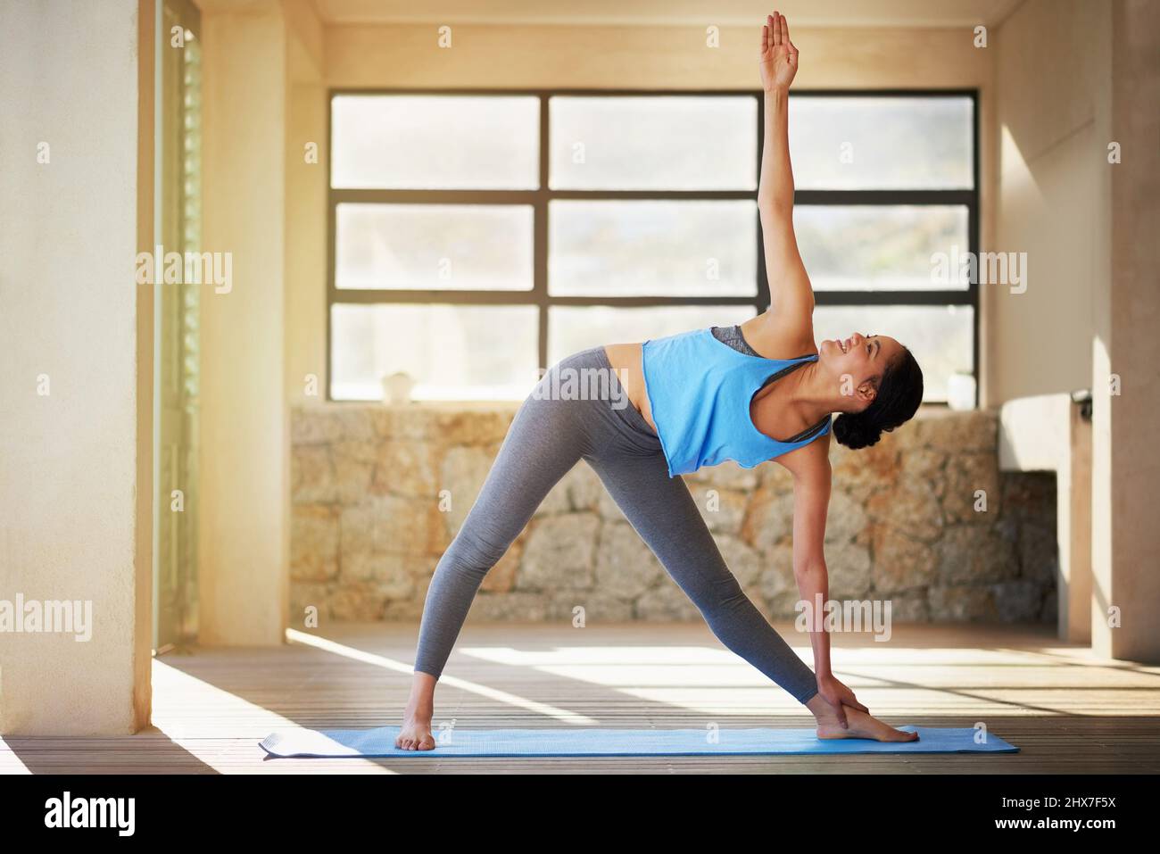 Durch Yoga ihr Fitnesslevel zu erhöhen. Aufnahme einer jungen Frau, die zu Hause Yoga praktiziert. Stockfoto
