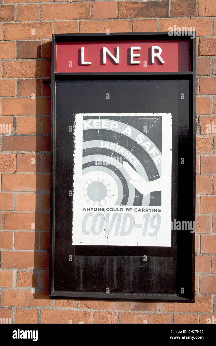 Eine moderne Botschaft über Covid, die auf einem LNER-Plakat am Bahnhof Quorn auf der Großen Zentralbahn zu sehen ist Stockfoto