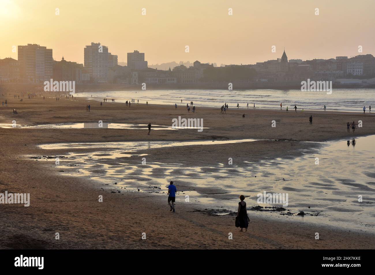Menschen am Strand Playa de San Lorenzo bei Sonnenuntergang in Gijon Asturias Spanien. Stockfoto