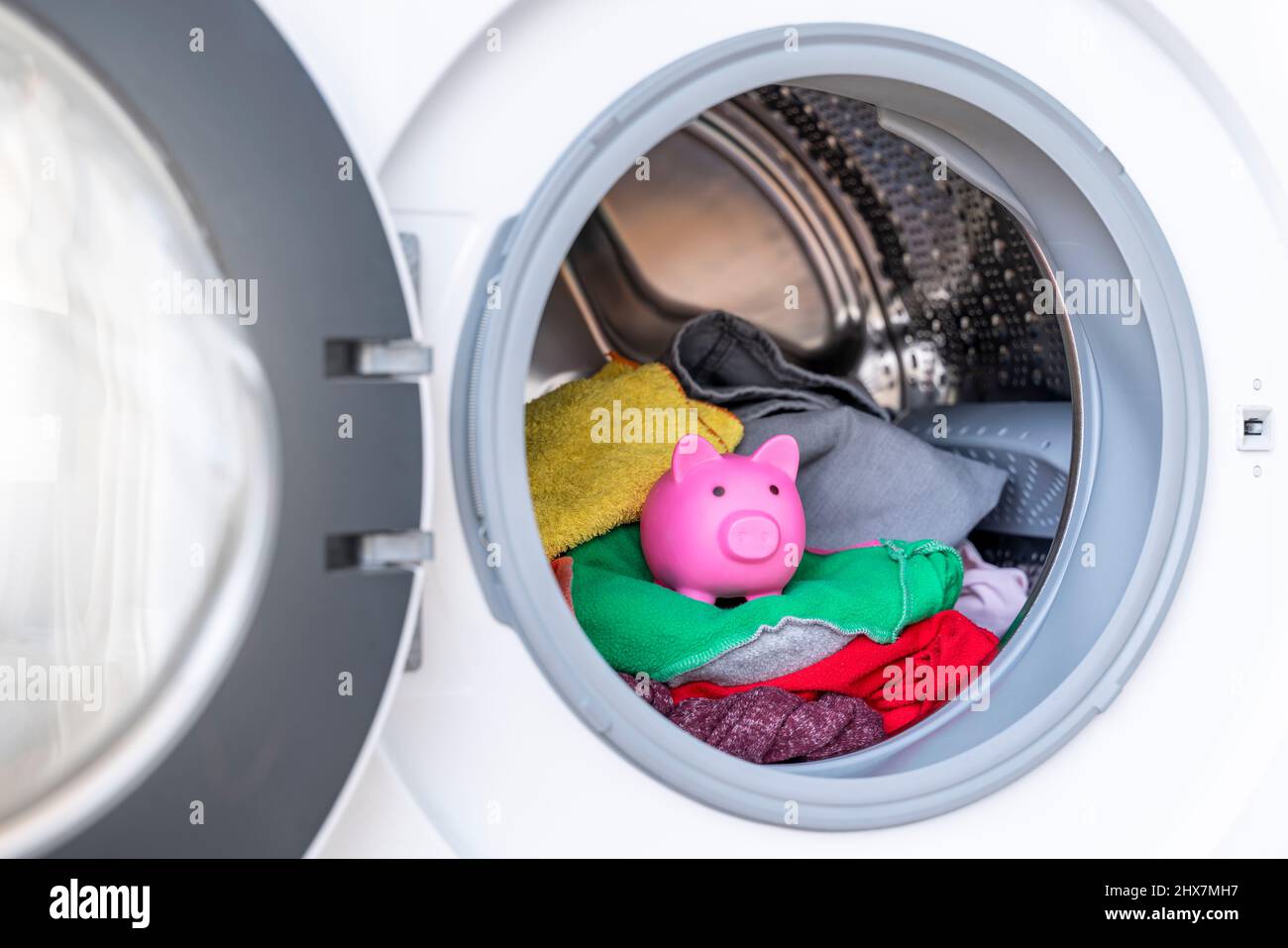 Konzept der Stromeinsparung mit einer Waschmaschine mit einem Sparschwein im Inneren Stockfoto