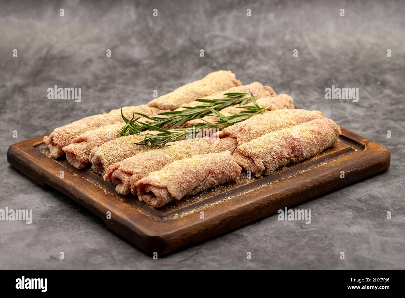 Rinderschnitzel auf dunklem Hintergrund. Köstliche rohe Fleischschnitzel, zubereitet mit Paniermehl und weißem Sesam. Stockfoto