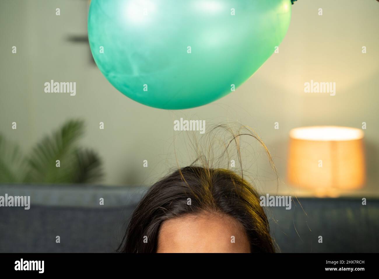 Nahaufnahme von spielenden Kindern, indem man einen Ballon auf das anziehende Haar legt - mit dem Wissen um statisches Ankleben auf das Haus, um Wissenschaft zu experimentieren und zu lernen. Stockfoto