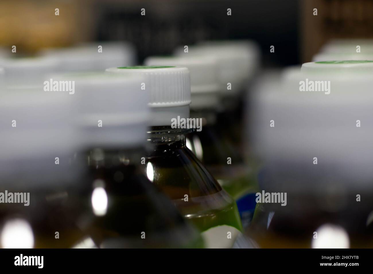 Eine Reihe von Tee-Plastikflaschen mit weißen Plastikkappen in einem Lebensmittelgeschäft. Stockfoto