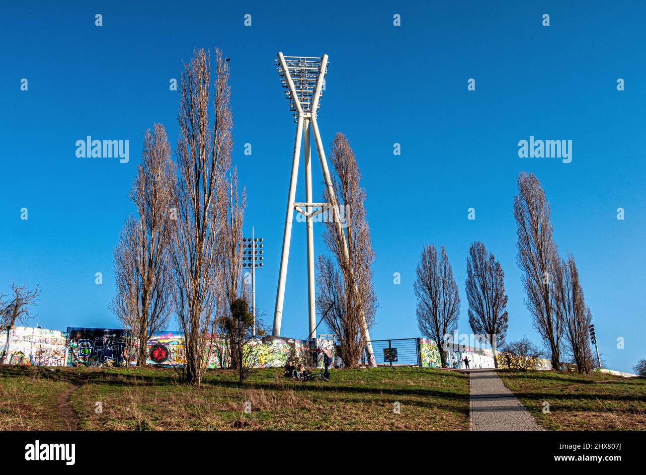 Stadtkunst - ehemalige Berliner Grenzmauer, gemalt von Straßenkünstlern im Mauerpark, Prenzlauer Berg, Berlin. Flutlicht im Friedrich-Ludwig-Jahn-Stadion Stockfoto