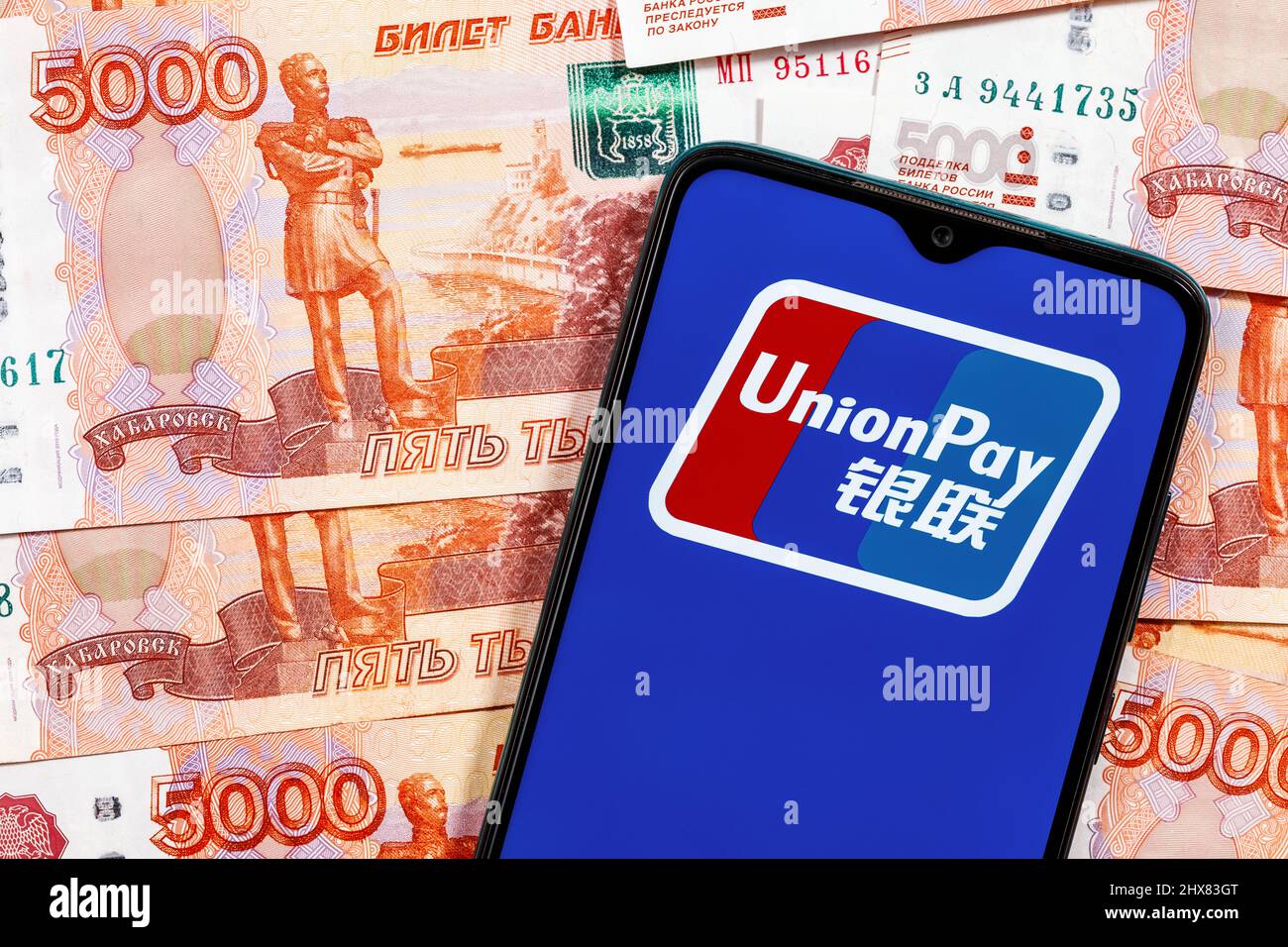 UnionPay ist ein chinesisches elektronisches Geldtransfersystem weltweit. UnionPay-Logo auf dem Smartphone-Bildschirm auf dem Hintergrund von Ruble-Banknoten. Stockfoto