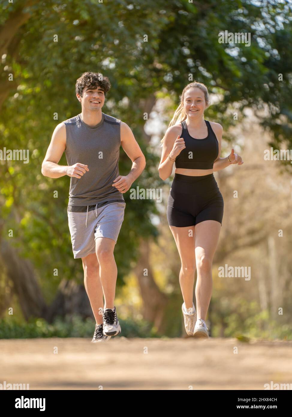 Junges Paar, das Sport macht, läuft auf einem Parkweg und lächelt Stockfoto