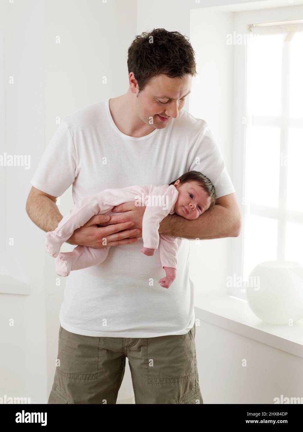 Mann hält Baby Mädchen an Unterarmen, 5 Wochen Stockfoto