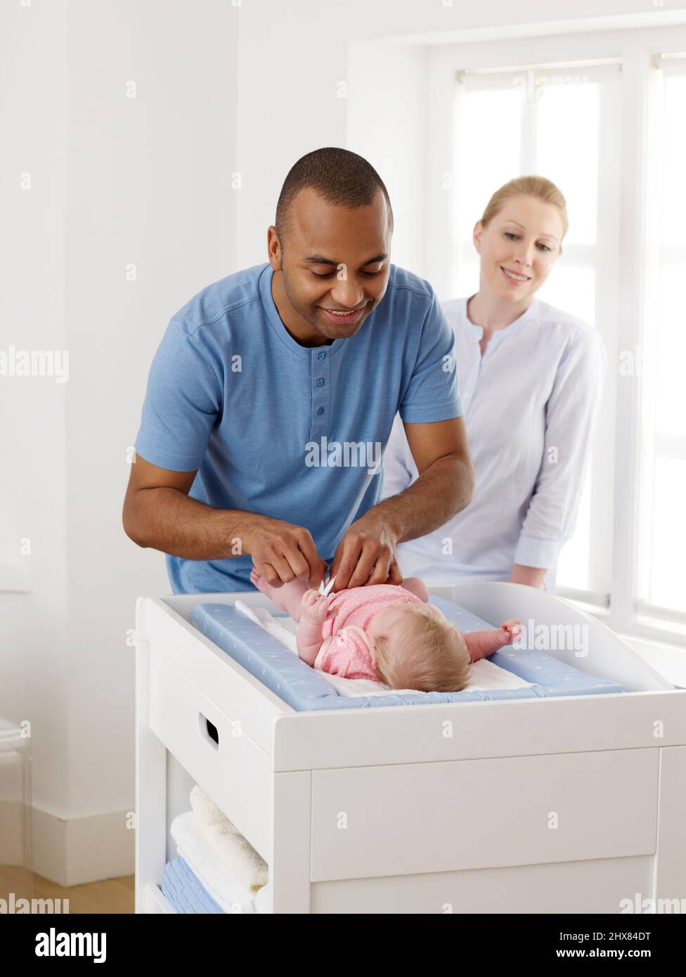 Mann und Frau blicken über ein Mädchen, das auf der Wechseleinheit liegt, 4 Wochen Stockfoto