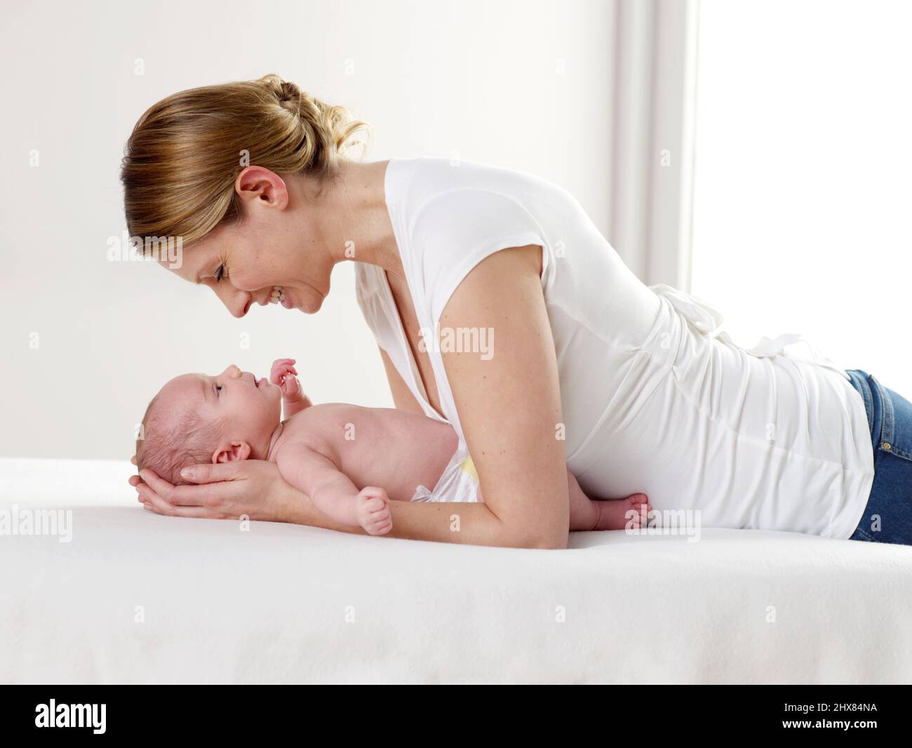 Frau schaut über Baby Junge, 8 Wochen Stockfoto