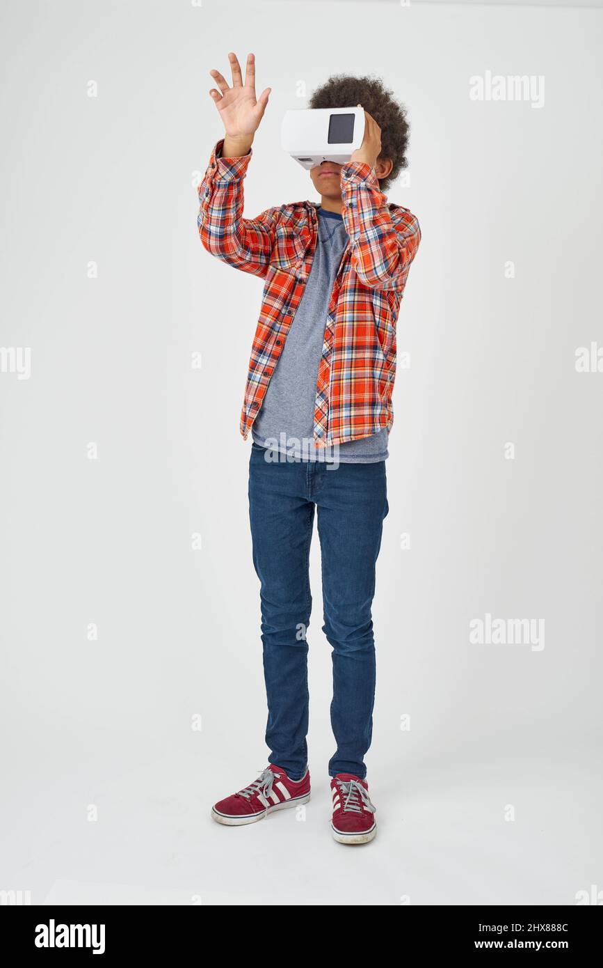 Kind steht und hält einen Virtual-Reality-Betrachter mit der Hand vor sich Stockfoto