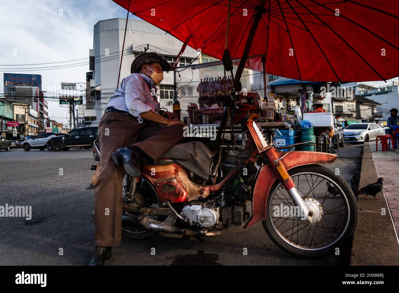 Surat Thani, Thailand. 10. März 2022. Ein Mann, der als Cowboy gekleidet ist, verkauft getrockneten Tintenfisch und heißen Tee aus seinem Motorrad-Wagen neben dem TAPI-Fluss in Surat Thani. Kredit: SOPA Images Limited/Alamy Live Nachrichten Stockfoto