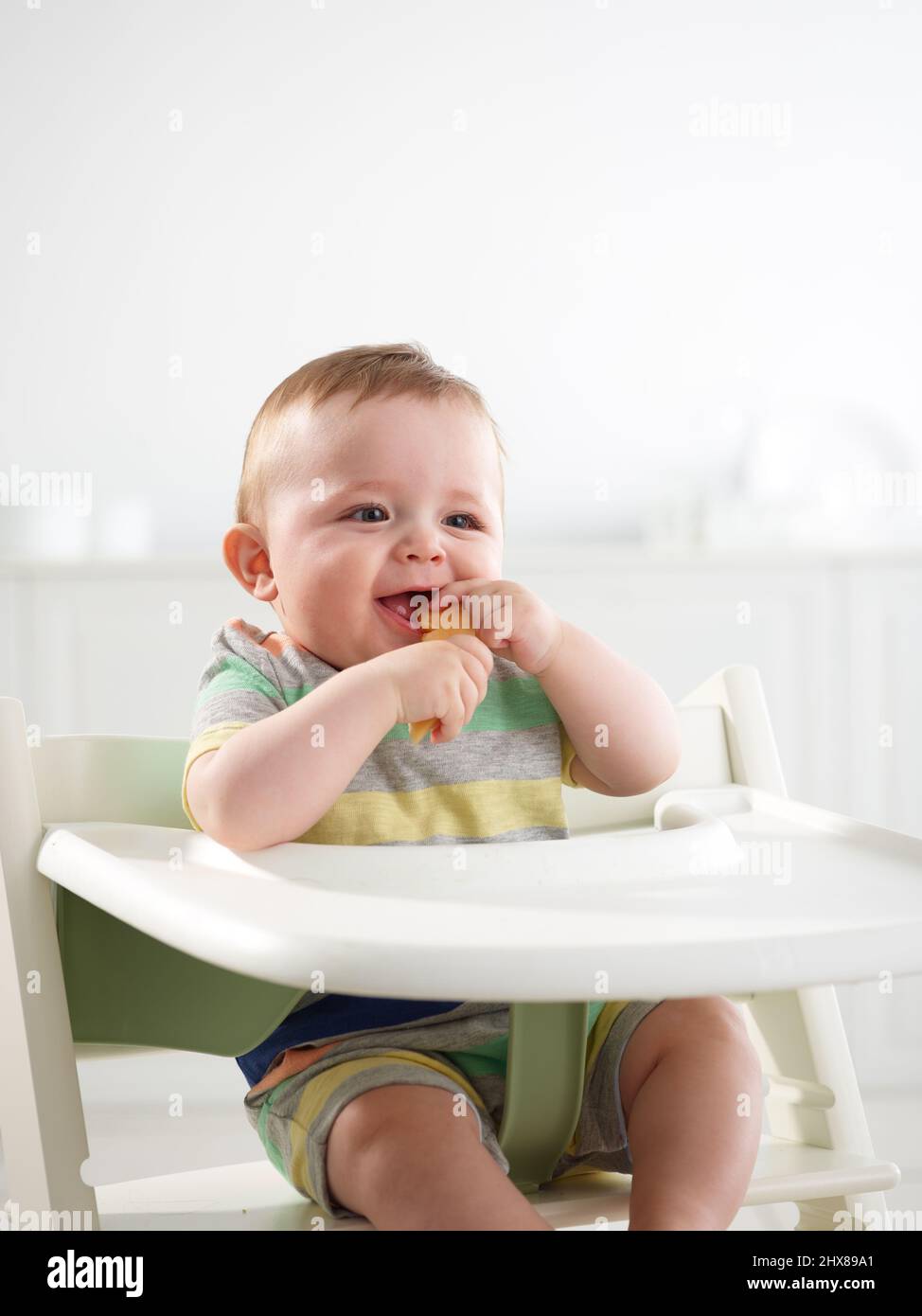 Baby im Alter von 7 Monaten essen im Hochstuhl Stockfoto