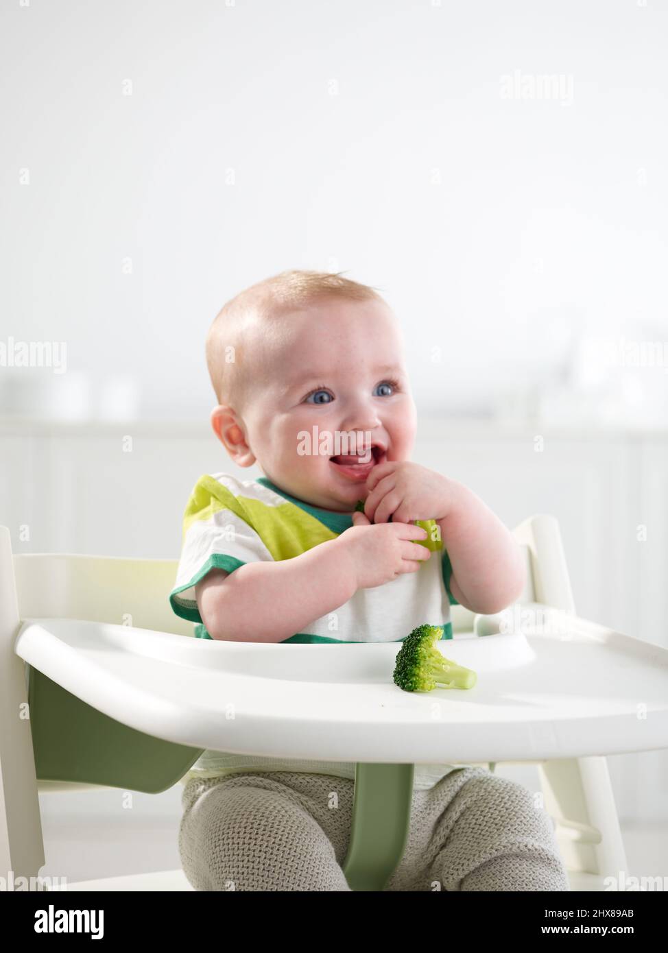 Baby im Alter von 6 Monaten essen im Hochstuhl Stockfoto