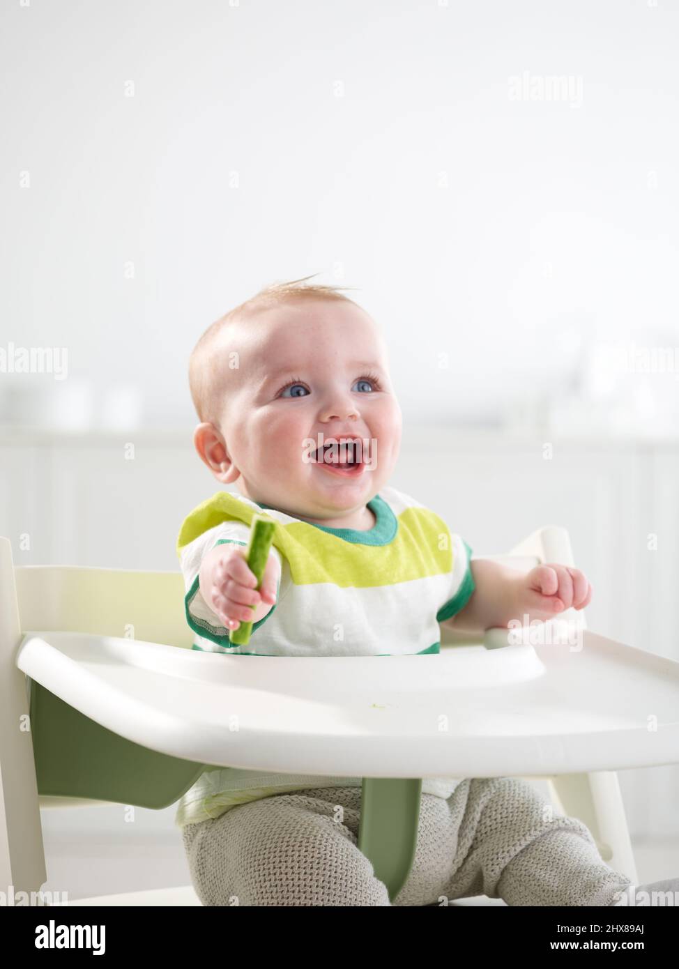 Baby im Alter von 6 Monaten essen im Hochstuhl Stockfoto