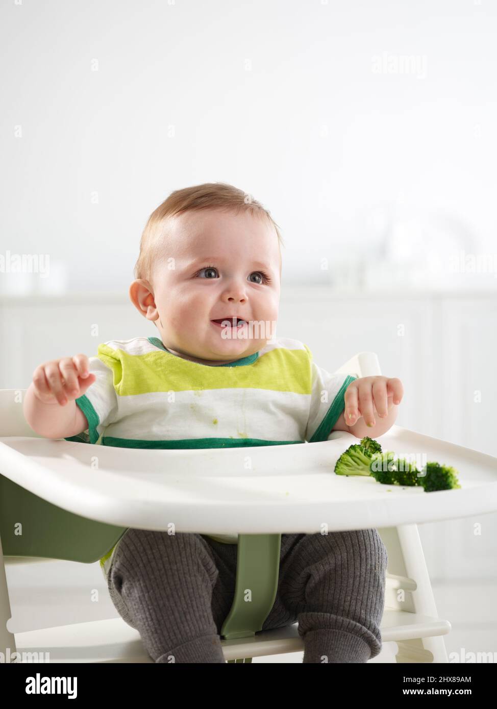 Baby im Alter von 7 Monaten essen im Hochstuhl Stockfoto
