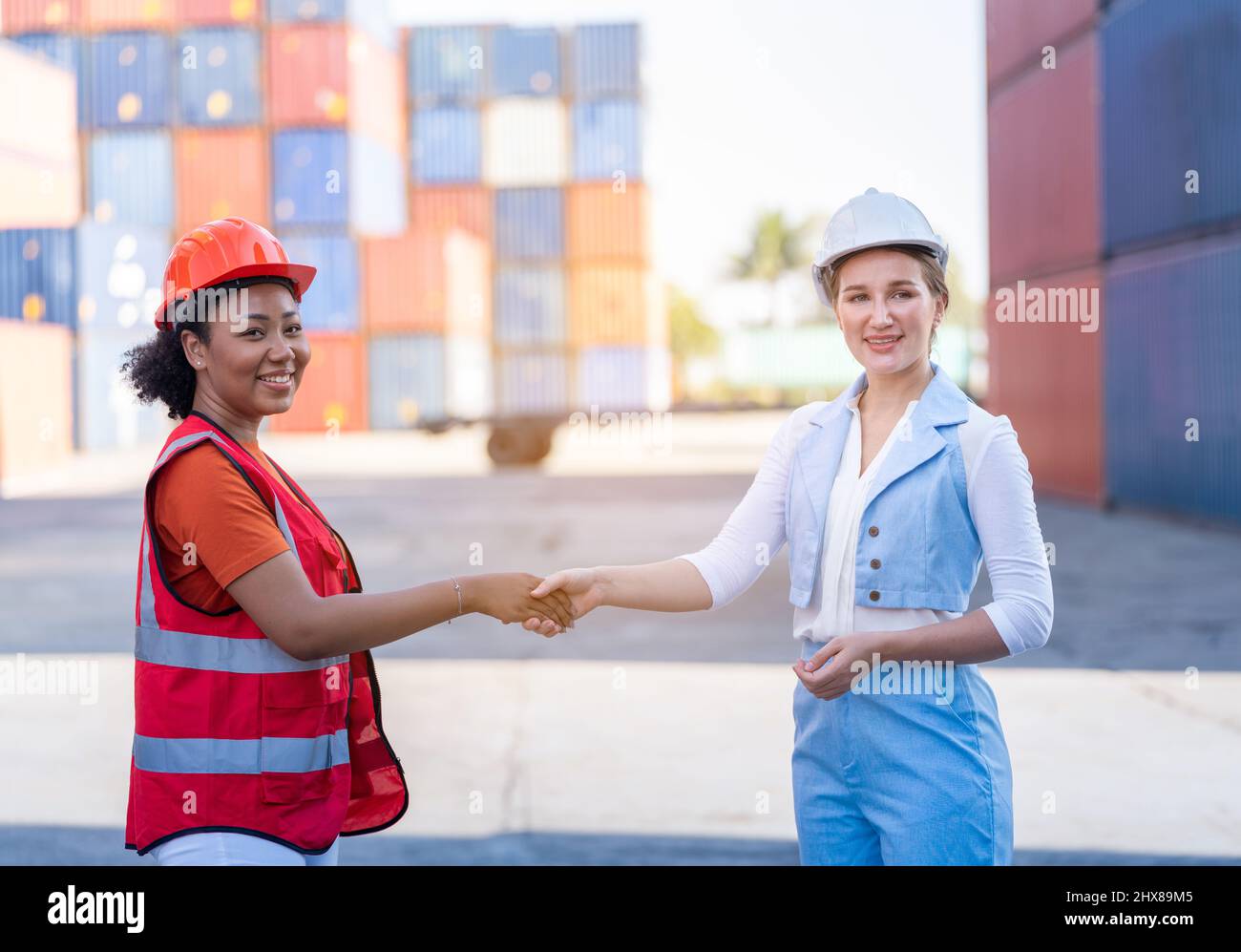 Lagergeschäft. Eine afroamerikanische Vorarbeiterin und eine CEO-Frau im Anzug schütteln die Hände und schließen nach Erfolg einen Job für Transport und Logistik ab Stockfoto