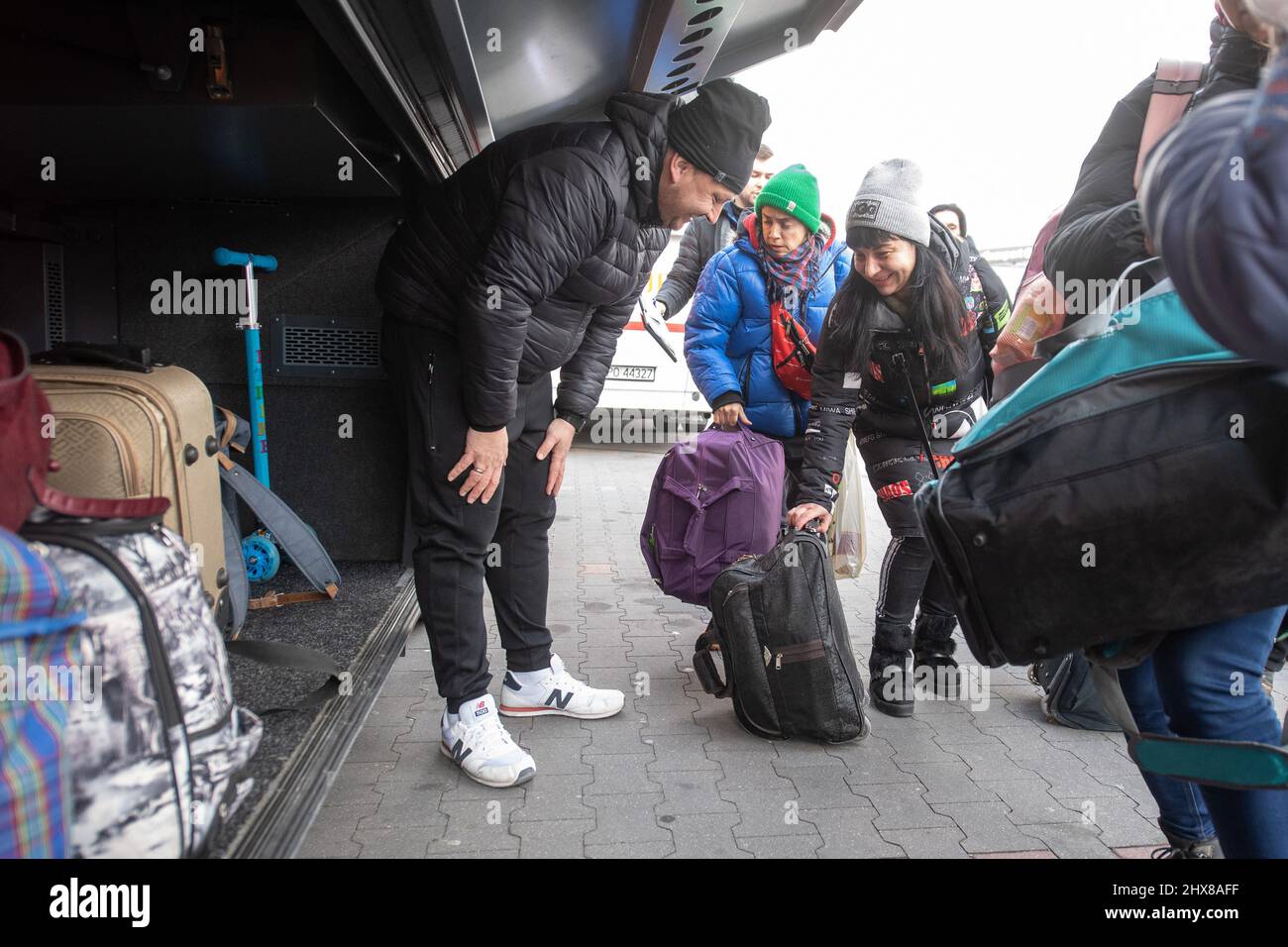 Przemysl, Polen. 10. März 2022. Pepe Palme (l) hilft, das Gepäck von Flüchtlingen in einen Bus zu verladen, der in einem Verteilzentrum nach Pforzheim fährt. Quelle: Sebastian Gollnow/dpa/Alamy Live News Stockfoto