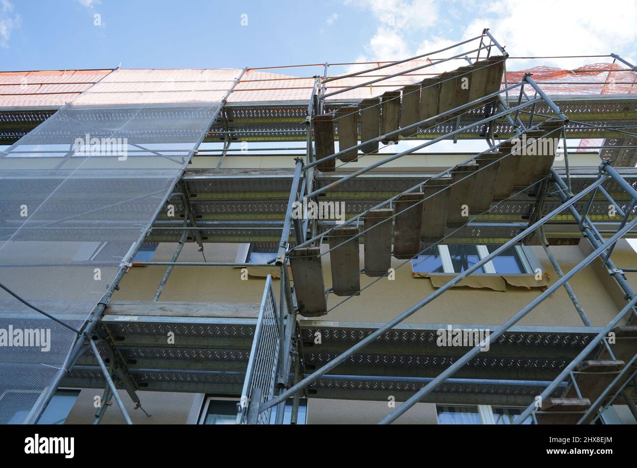 Gerüst und Schutznetz an einer Hausfassade. Low-Angle-Ansicht. Ausschnitt einer Rekonstruktion des Hauses. Stockfoto