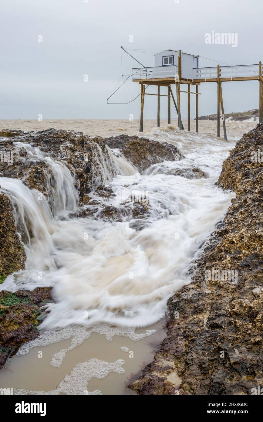 Meereswellen brechen Felsen an der französischen Atlantikküste mit Angelhütte in der Nähe von La Rochelle, Charente Maritime, Frankreich Stockfoto