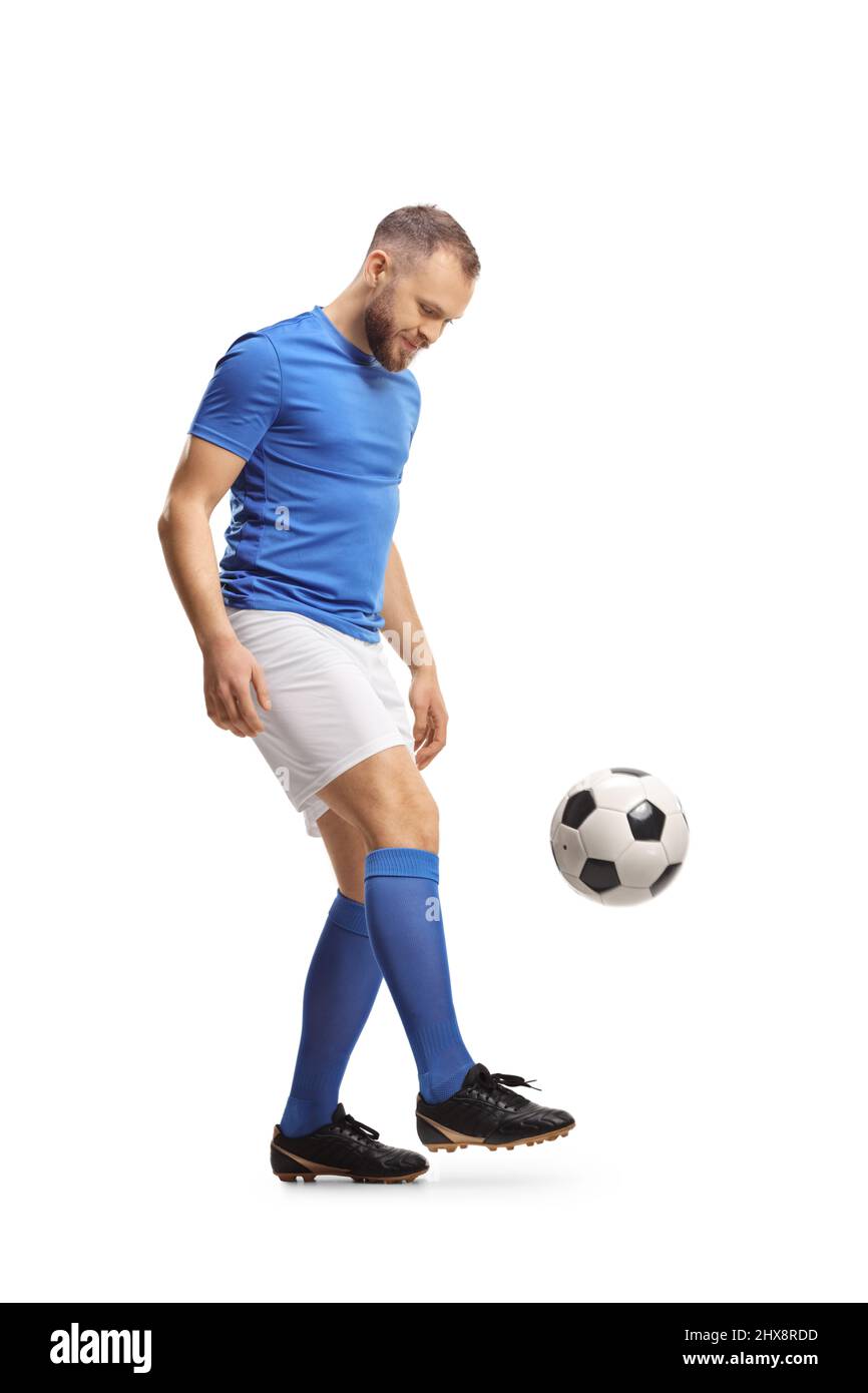 Ganzkörperaufnahme eines Fußballers mit blauem Oberteil und weißen Shorts, der einen Ball auf weißem Hintergrund abtritt Stockfoto