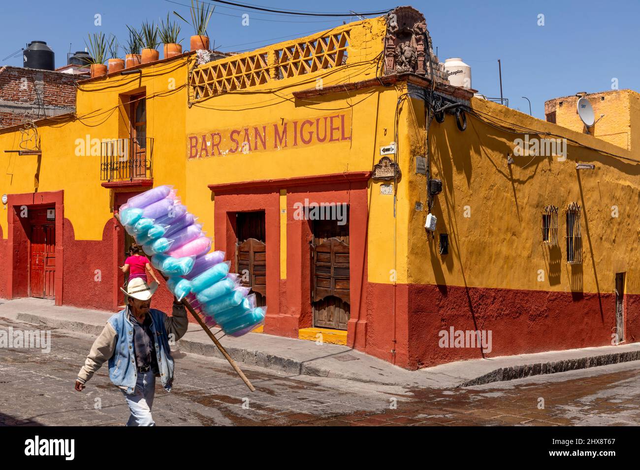 Mexiko, der Staat Guanajuato, San Miguel de Allende, Mann, der Zuckerwatte verkauft, läuft an der Bar San Miguel vorbei Stockfoto