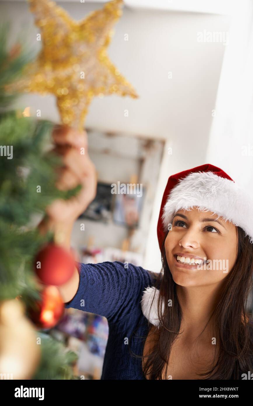 Die letzten Feinheiten anwenden. Ausgeschnittene Aufnahme einer schönen Frau, die einen Weihnachtsbaum schmückt. Stockfoto
