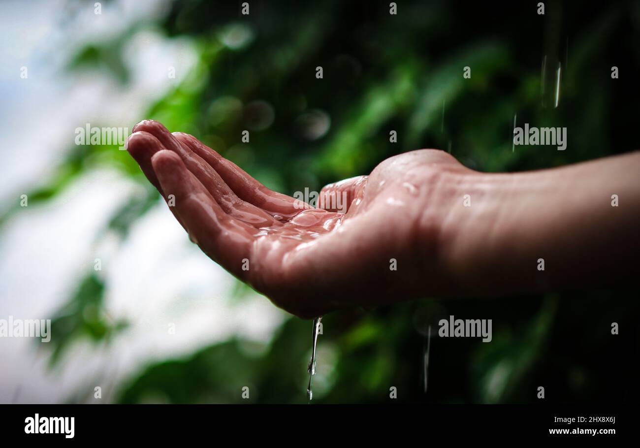 Hand eines dreizehn Jahre alten Jungen, der bei Regen Regentropfen fängt Stockfoto