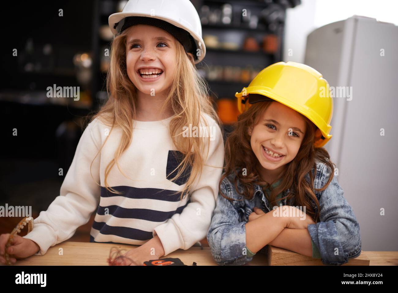 Dinge zu schaffen macht so viel Spaß. Aufnahme von zwei kleinen Mädchen, die mit Werkzeugen in Hüten herumspielen. Stockfoto