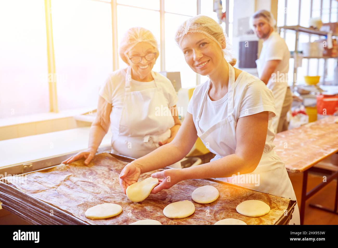 Das Team der Bäckerei arbeitet zusammen, um Auszubildende im Handwerk auszubilden Stockfoto