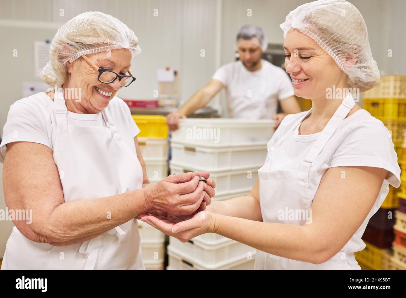 Ältere Frau als Bäcker, die zusammen mit einem Lehrling in der Bäckerei Kekse backen Stockfoto