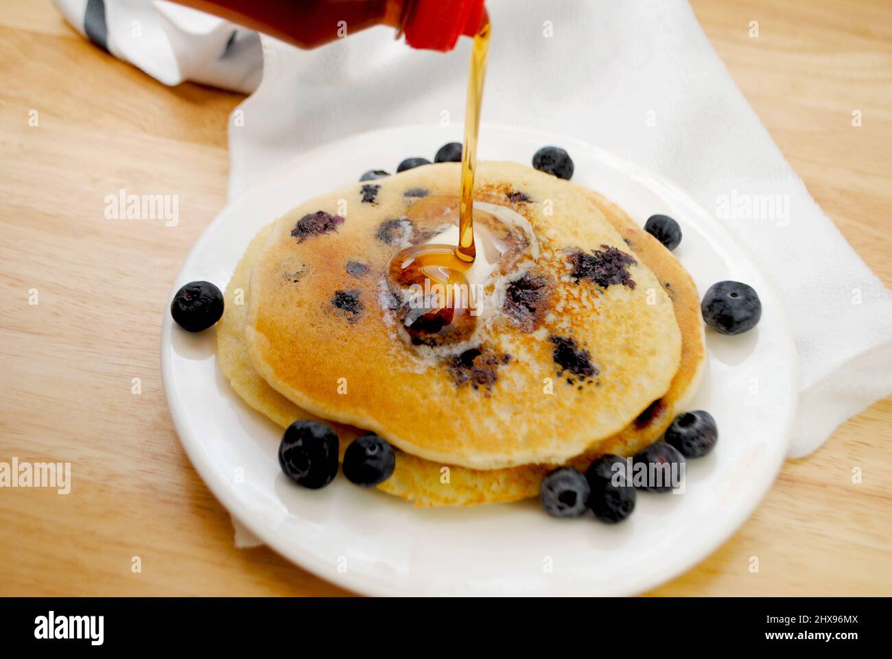 Gießen Sie Sirup auf Heidelbeer-Pfannkuchen mit Butter Stockfoto