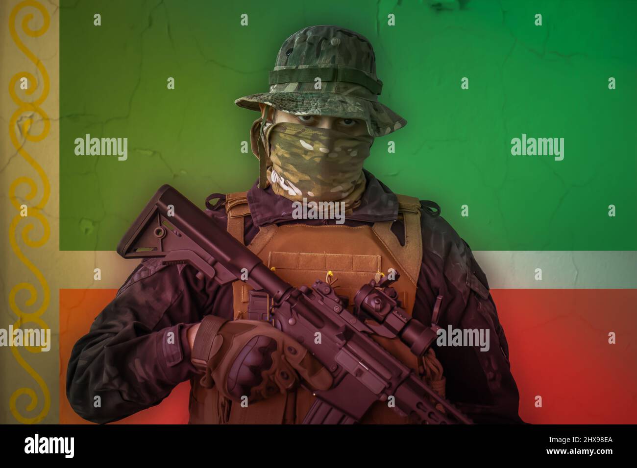 Wütender tschetschenen-Soldat mit Gewehr und tschetschenien-Flagge als Hintergrund dahinter bewaffnet Stockfoto