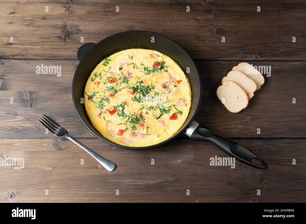 Spiegeleier mit Petersilie in Pfanne auf einem dunklen Holztisch, hausgemachtes Frühstück. Stockfoto