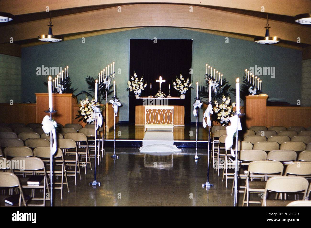 Eine Kapelle oder Kirchenheiligtum für ein besonderes Ereignis mit vielen angezündeten Kerzen geschmückt, wahrscheinlich für eine Hochzeit oder eine besondere religiöse Zeremonie Ca. 1961 Stockfoto