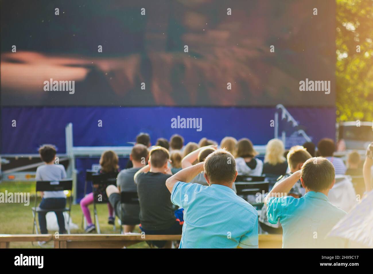 Eine Gruppe von Menschen, die eine Freiluftkinoleinwand beobachten. Stockfoto