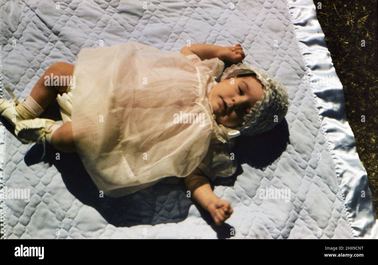 Baby liegt auf einer blauen Decke in einem Hof ca. 1955-1959 Stockfoto