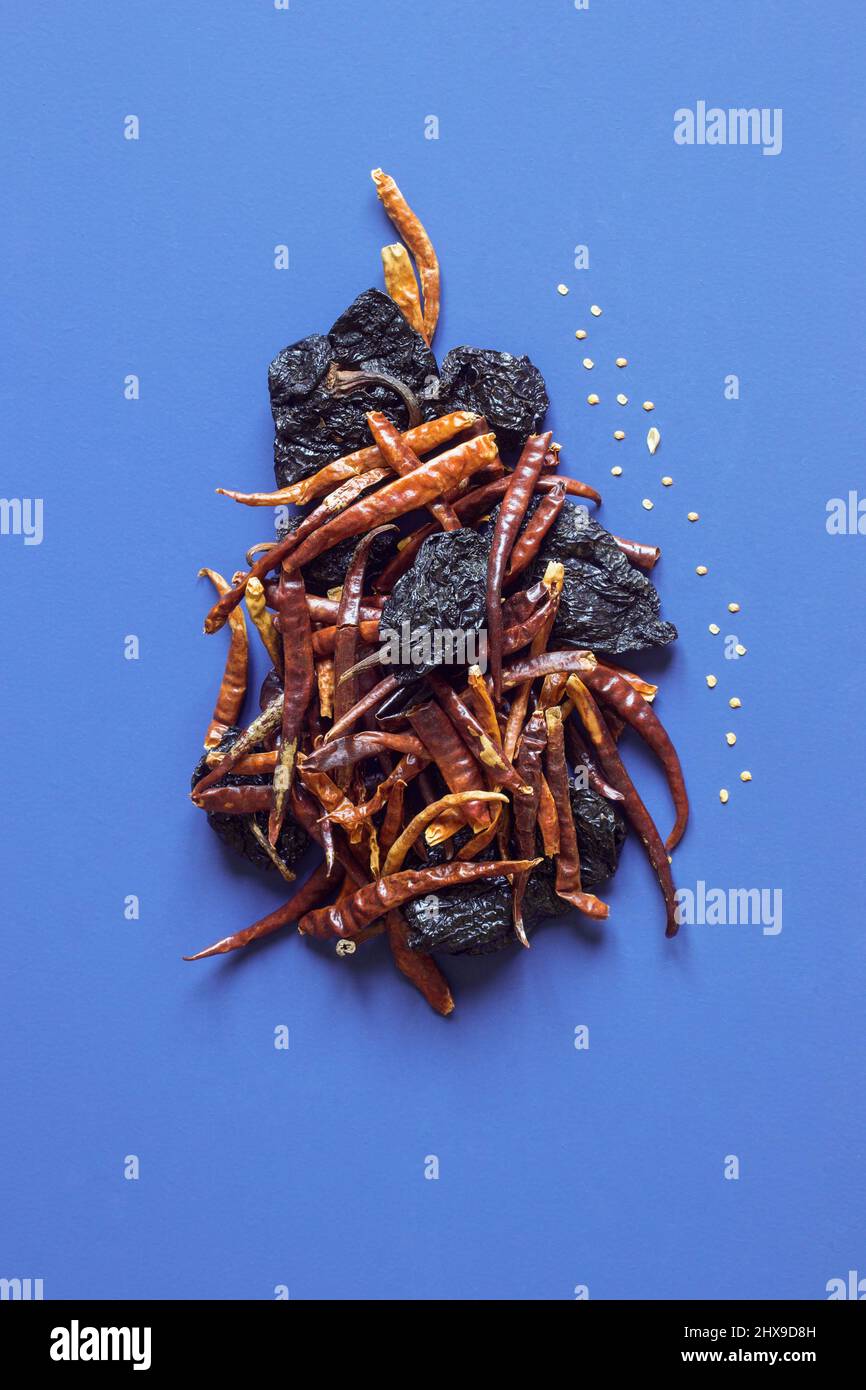 Stillleben von dehydrierten und getrockneten Chilischoten bilden eine abstrakte Figur auf buntem Gemüsestudio-Hintergrund. Gesundheit und Herz. Stockfoto