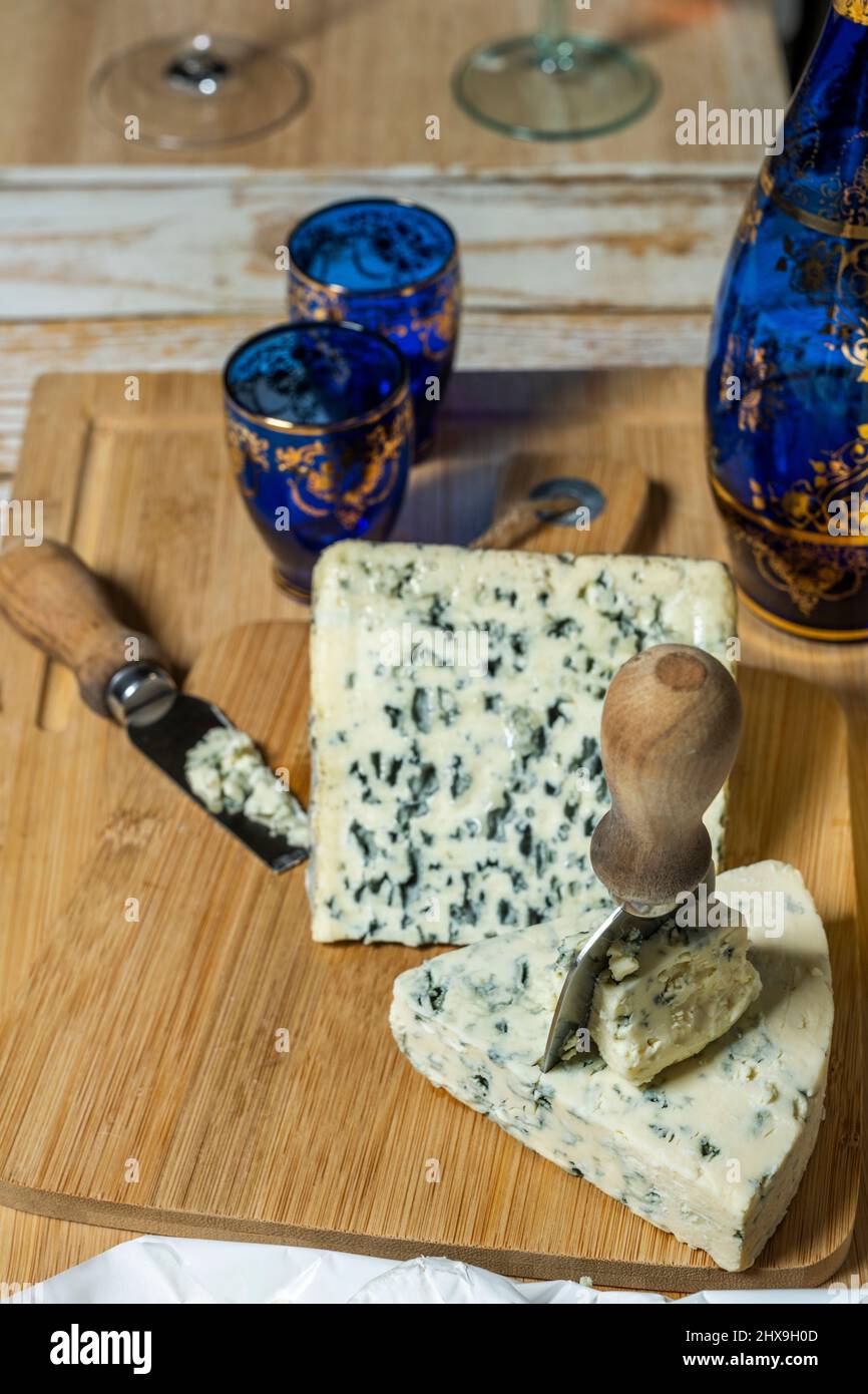 Ein Paar Kuhblaue Käsetacos mit Käsemessern und eine blaue Glasflasche mit passenden Gläsern auf Bambusholz Stockfoto